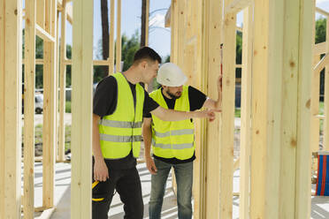 Engineers examining wooden frame and discussing at construction site - SEAF02039