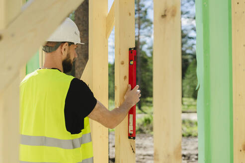 Ingenieur misst Holz mit Nivelliergerät auf der Baustelle - SEAF02041