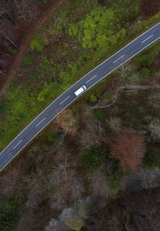 Österreich, Oberösterreich, Drohnenansicht eines Autos auf einer asphaltierten Straße, die sich durch einen Herbstwald zieht - WWF06563