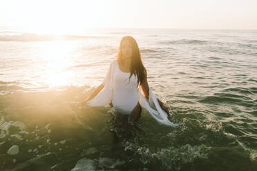 Stehende und spritzende Frau inmitten des Meeres am Strand - SIF00978