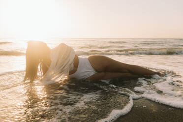 Young woman taking bath in sea during sunset stock photo