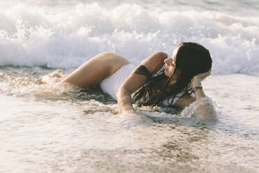 Woman with eyes closed lying in water at beach - SIF01001