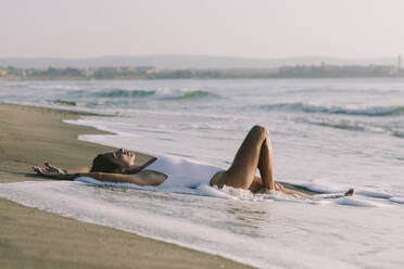 Frau mit erhobenen Armen am Meer liegend am Strand - SIF01003