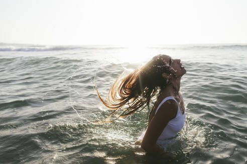 Woman tossing hair in sea water at beach - SIF01007