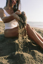 Woman playing with sand at beach - SIF01011
