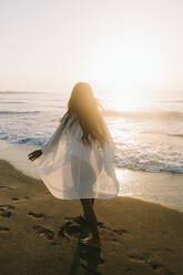 Woman walking barefoot by sea at beach - SIF01014
