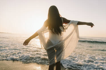 Mature woman with arms outstretched standing near sea at dawn - SIF01017