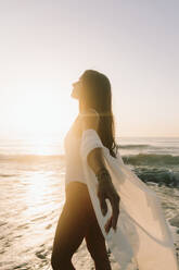 Carefree woman standing near sea at dawn - SIF01018