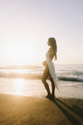 Woman wearing swimwear standing near sea at dawn - SIF01020