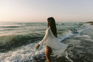 Frau mit langen Haaren geht am Strand in der Nähe des Meeres spazieren - SIF01021