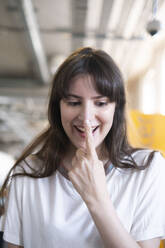 Glückliche Frau berührt Nase mit Finger - AMWF01831
