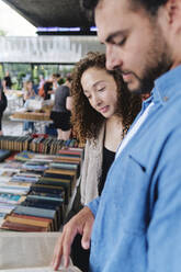 Lächelnde Frau mit Mann, der in einem Geschäft ein Buch liest - ASGF04653