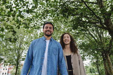Smiling man and woman walking in park - ASGF04660