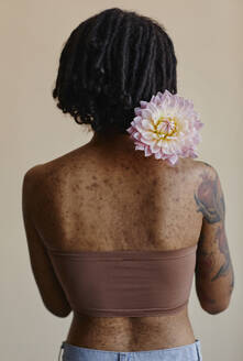 Frau mit Aknenarben hält Pfingstrose Blume gegen braunen Hintergrund - KPEF00265