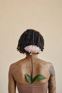 Young woman with flower in tube top against brown background - KPEF00267