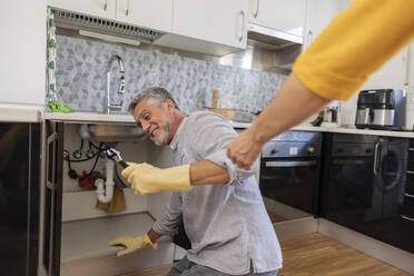 Hand eines helfenden Mannes bei der Reparatur eines Wasserhahns in der Küche zu Hause - JCCMF10737