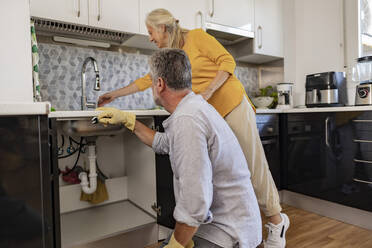 Mann und Frau reparieren Wasserhahn in der Küche zu Hause - JCCMF10738