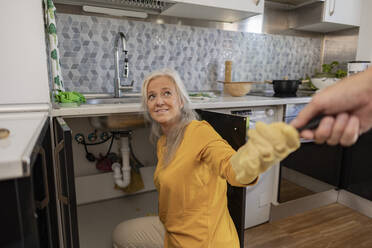 Reife Frau macht Klempnerarbeiten in der Küche zu Hause - JCCMF10739