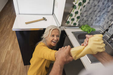 Glückliche Frau hält Hand des Mannes in der Küche zu Hause - JCCMF10742