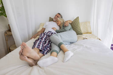 Reifes Paar entspannt zusammen auf dem Bett zu Hause - JCCMF10757