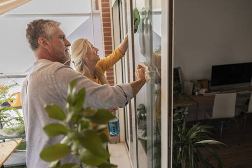 Mann und Frau putzen Hausfenster - JCCMF10810