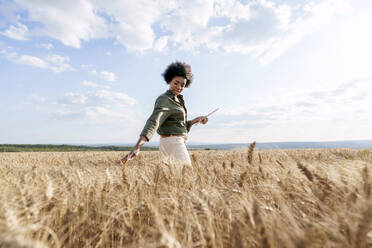 Junger Afro-Agronom mit Tablet-PC bei der Untersuchung von Gerste im Feld - AAZF01176