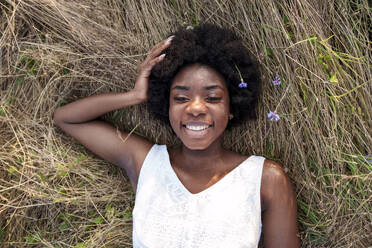 Happy young woman relaxing on dry grass - AAZF01204