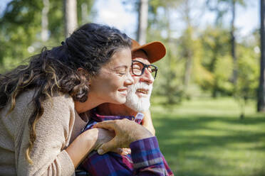 Happy caregiver embracing retired senior man at park - IKF01330