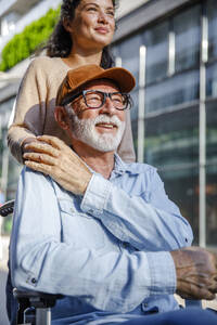 Smiling caregiver with hand on senior man's shoulder - IKF01367