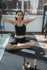 Frau mit geschlossenen Augen übt Yoga zu Hause - ANAF02173
