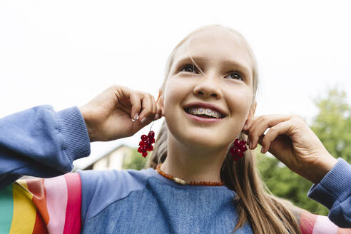 Lächelndes Mädchen hält frische rote Johannisbeeren an den Ohren - EYAF02846