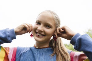 Glückliches blondes Mädchen spielt mit frischen roten Johannisbeeren - EYAF02847