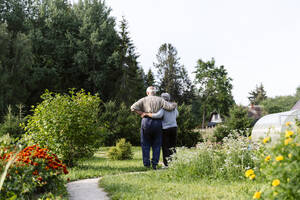 Älteres Paar umarmt sich im Garten - EYAF02854