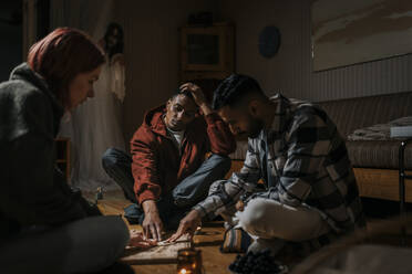 Freunde berühren das Ouija-Brett, während der Geist im Hintergrund in der Hütte ist - MASF39588