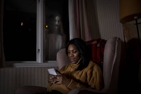 Geist schaut durch das Fenster auf eine Frau, die in der Kabine ein Mobiltelefon benutzt - MASF39612
