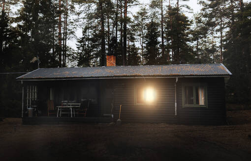Exterior of log cabin with trees in background at sunset - MASF39620
