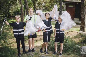 Ganzkörperporträt von lächelnden männlichen Freiwilligen, die Müllsäcke halten - MASF39632