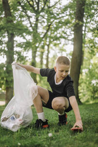 Ein Junge sammelt Müll auf dem Rasen und tut seinen Teil für die Umwelt - MASF39655