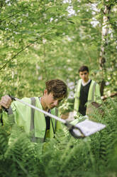 Ein junger Mann sammelt Plastikmüll aus einer Pflanze, um die Umwelt zu schützen - MASF39675