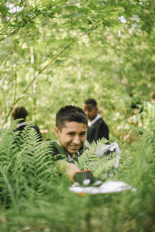 Freudiger Junge sammelt Plastik von einer Pflanze auf und hilft so, die Umwelt zu schützen - MASF39676