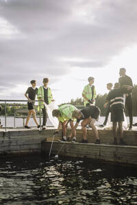 Junge reinigen den See vom Steg aus mit Blick auf den Himmel - MASF39688