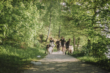 Junge und Trainer joggen auf einem grünen Fußweg umgeben von Pflanzen - MASF39695