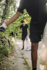 Jugendliche sammeln Plastikmüll von der Straße auf und helfen so, die Umwelt zu schützen - MASF39710