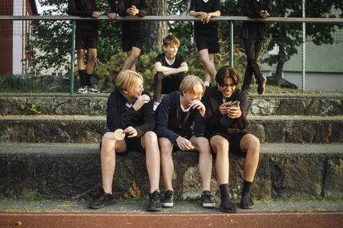 Jugendliche teilen fröhlich ein Smartphone untereinander - MASF39734