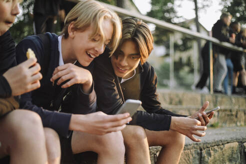 Jugendliche teilen glücklich ein Smartphone und genießen die gemeinsame Zeit - MASF39736