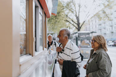 Smiling male and female senior friends shopping from store - MASF39744