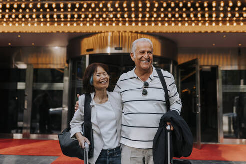 Glückliche männliche und weibliche ältere Freunde stehen vor einem Kino - MASF39759
