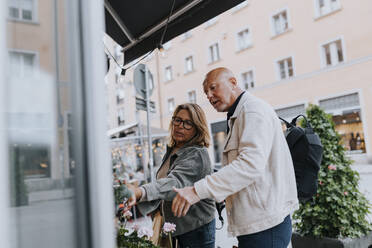 Male and female senior friends shopping together at street - MASF39771