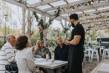 Männliche und weibliche ältere Freunde geben dem Kellner, der im Restaurant steht, eine Essensbestellung auf - MASF39776