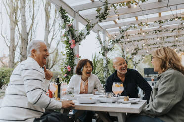 Fröhliche männliche und weibliche ältere Freunde lachen beim Essen im Restaurant - MASF39784